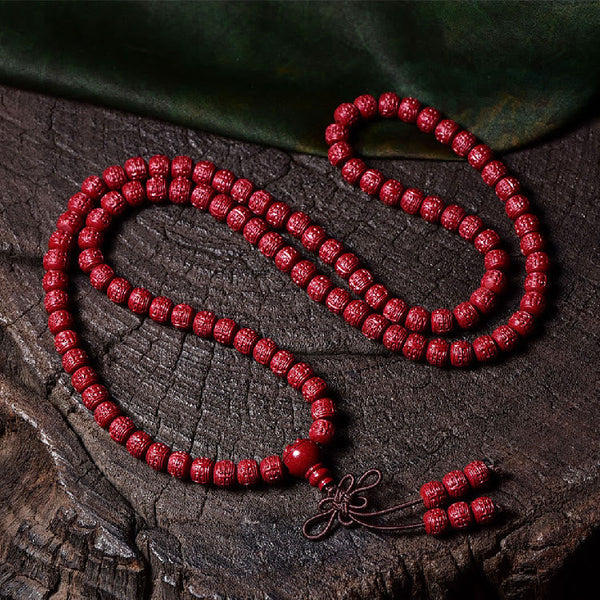 108 Mala Beads Cinnabar Bracelet – Flat lay on dark wood grain, red prayer beads