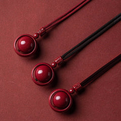 Cinnabar PiXiu Necklace – Three pendants flat lay with red and black cords on red surface, feng shui necklace
