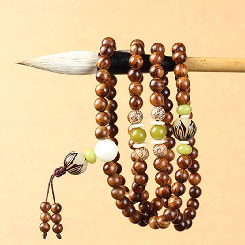 Tibetan Rosewood Bodhi Seed Mala Bracelet hanging on calligraphy brush, showing olive green jade beads and carved bodhi seed accents, white guru bead, traditional 108-bead mala necklace with brown cord tassel