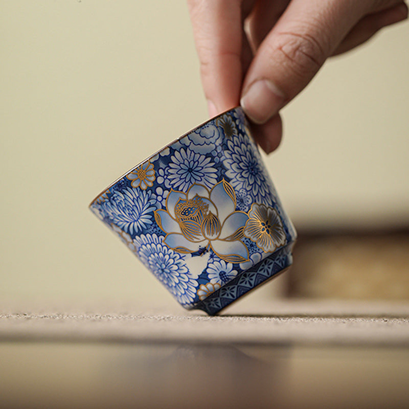 Lotus Chrysanthemum Ceramic Tea Cup - Finger-held blue porcelain with gold floral highlights, delicate