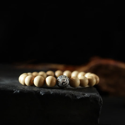 Peach Wood Yin Yang Bracelet – Yin yang metal bead on cream wood beads on dark stone, spiritual balance