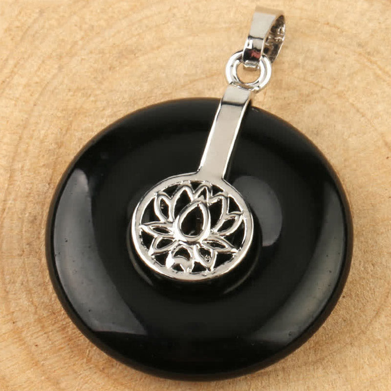 Crystal Amethyst Pink Crystal Lotus Necklace – Black onyx donut pendant overhead view on wood, polished obsidian with silver lotus filigree