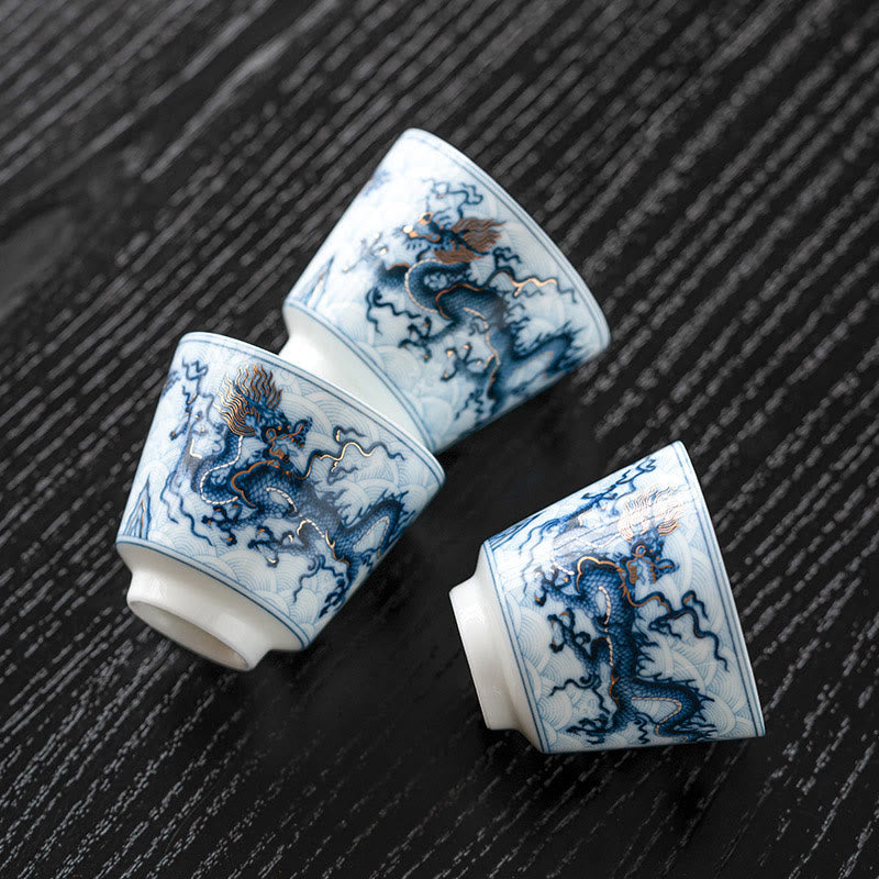 Blue & White Dragon Ceramic Teacup – three cups scattered on dark wood, dragon and wave patterns, traditional