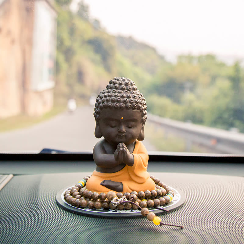 Small Buddha Purple Clay Decoration – anjali mudra figure on dashboard with hillside bokeh and green accent mala, mindful com