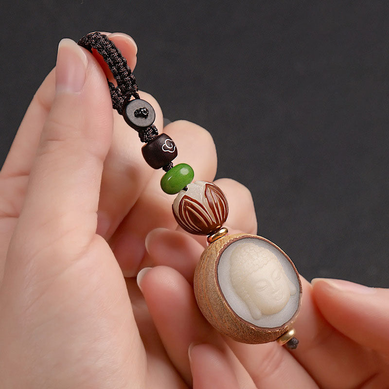 Bodhi Seed Blessing Keychain - handheld closeup revealing carved Buddha face inside rough seed shell between fingers, serenity