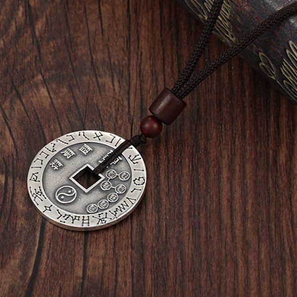 Bagua Yin Yang Obsidian Necklace - silver coin with yin-yang engravings on cord, wooden background