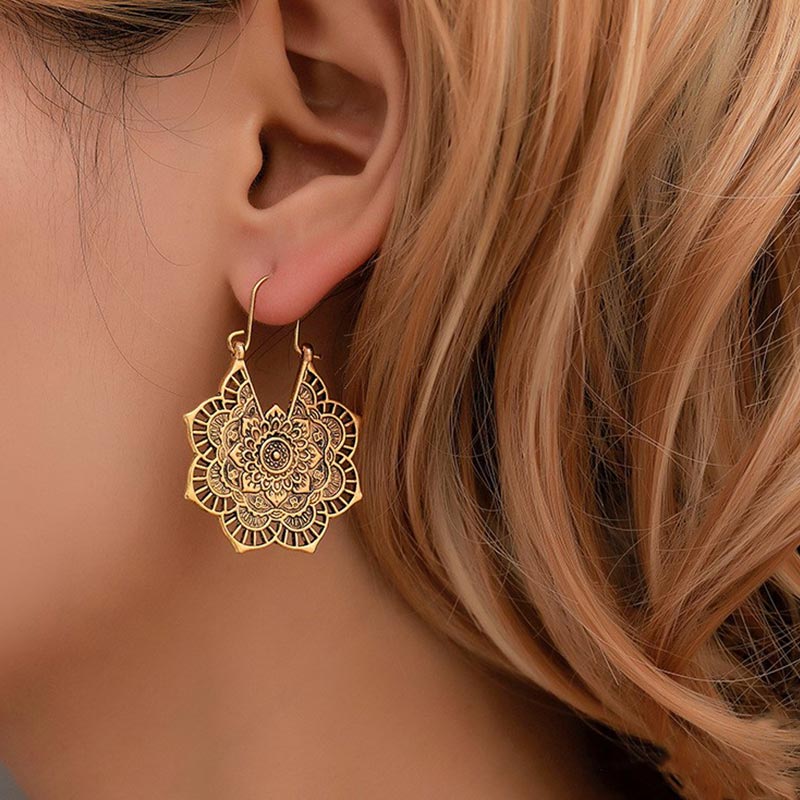 Tibetan Copper Lotus Engraving Drop Earrings – Gold-tone filigree mandala teardrop earring with laser-cut lotus pattern worn on model's ear