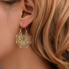 Tibetan Copper Lotus Engraving Drop Earrings – Gold-tone filigree mandala teardrop earring with laser-cut lotus pattern worn on model's ear