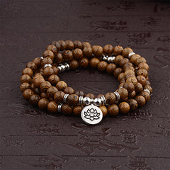 Tibetan Lightning Strike Wood Mala – coiled wrap with lotus charm on dark carved surface, front-view