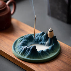 Ceramic Backflow Incense Burner – Blue-green mountain dish with smoke pooling in valley, teapot nearby, zen decor