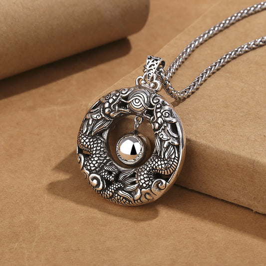Double Dragon Pendant Necklace three-quarter view, oxidized copper detail, rolled paper prop, protection jewelry