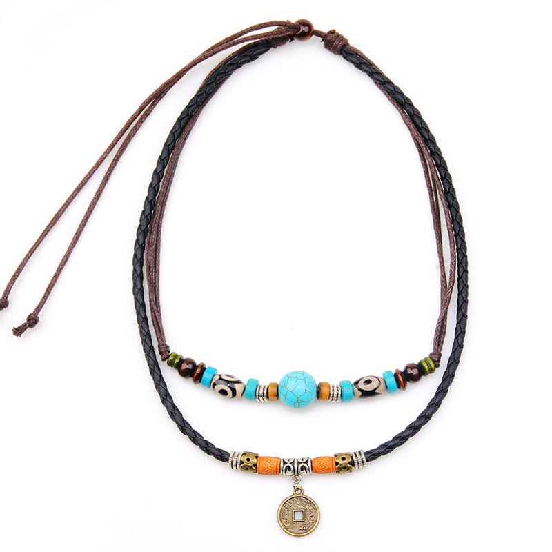 Turquoise Dzi Bead Protection Necklace – double-strand layered design with large turquoise center bead, traditional Tibetan Dzi eye pattern beads, orange amber accents and antique brass coin pendant on braided leather cord, flat-lay on white background