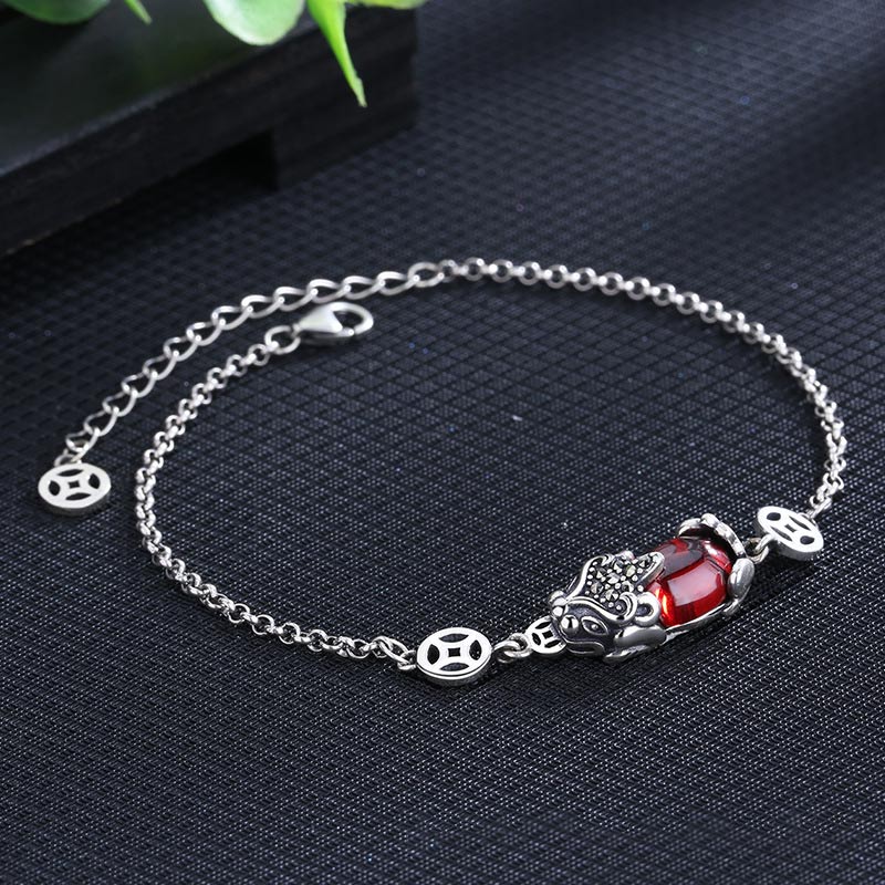 Copper Garnet PiXiu Wealth Bracelet – Silver chain with red garnet PiXiu on black fabric, green leaf accent, protection jewelry