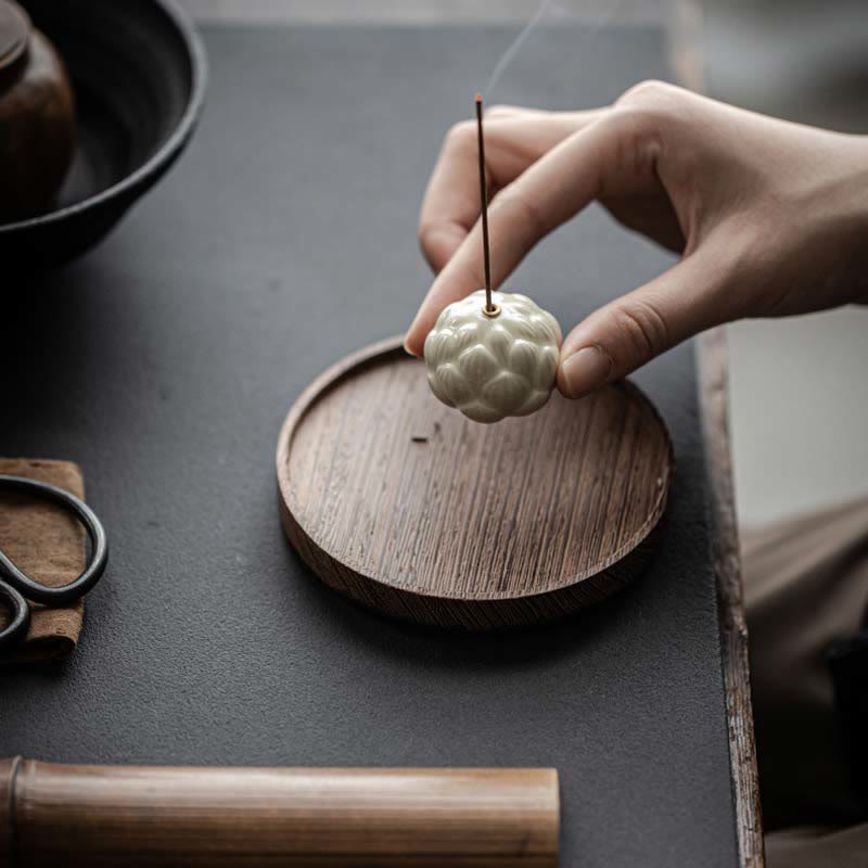 Ceramic Lotus Incense Burner held by hand with tea ceremony accessories, meditative