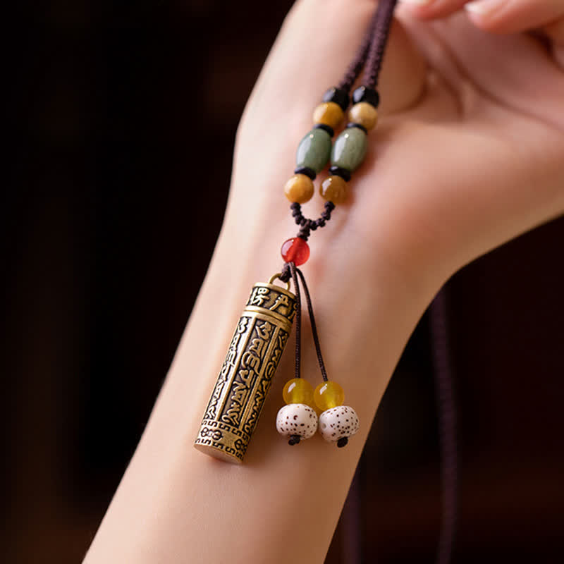 Ethnic Tibetan mantra pendant necklace with antique brass cylinder, olive jade beads, amber accents, bodhi seed tassels, and brown braided cord
