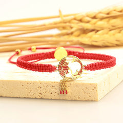 Tibetan Red String Koi Fish Bracelet – red cord on stone with wheat background, gold lotus bird charm and dangles