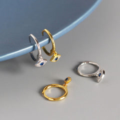 Evil Eye Huggie Hoop Earrings Hanging on Blue Ceramic Plate, Sterling Silver Protection