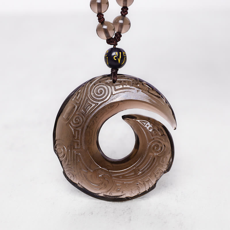 Black Obsidian Ice Obsidian Pendant Necklace – Smoky quartz translucent spiral pendant with crescent cutout and traditional Chinese cloud motif relief carving, matching brown-toned beads with gold mantra bead, black cord, white background, healing stone amulet