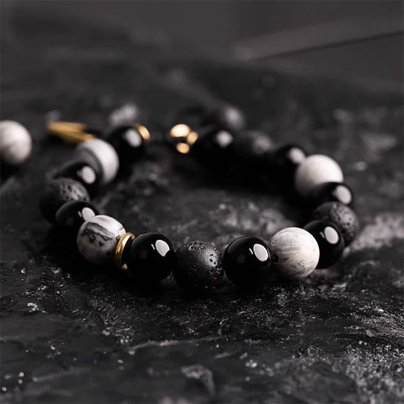 Black Obsidian Lava Rock Yin Yang Bracelet - low angle on dark slate, gold clasp, polished obsidian beads