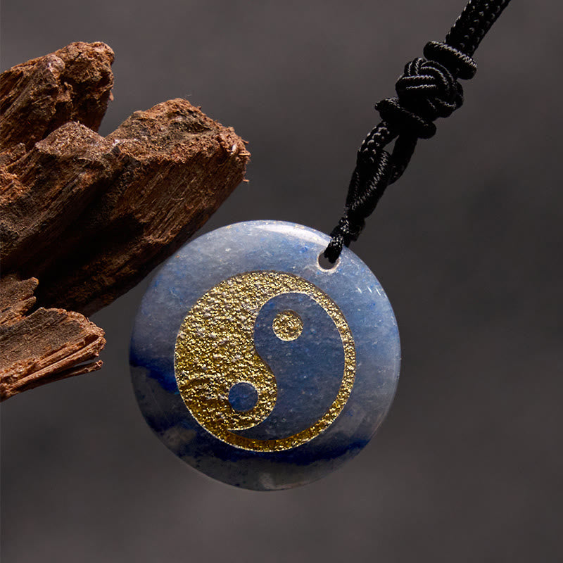 Yin Yang Crystal Necklace – Blue sodalite stone pendant with gold yin-yang engraving on black cord, polished gemstone with na