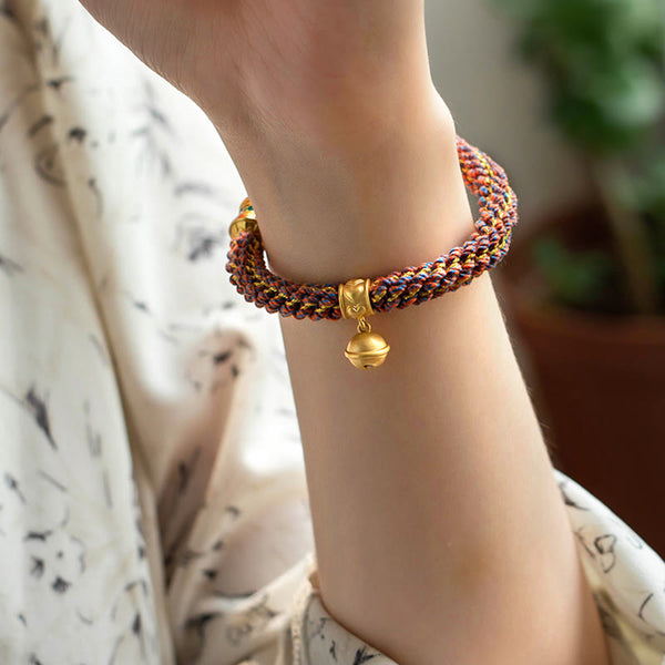 Om Mani Padme Hum Braided Bracelet – Side wrist view featuring gold bell charm and multi-strand woven cord texture