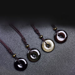 Tibetan obsidian protection necklace set showing four ping'an kou pendant varieties in glossy black smoky gray golden sheen and mahogany obsidian with gold-inscribed mantra beads on braided cords