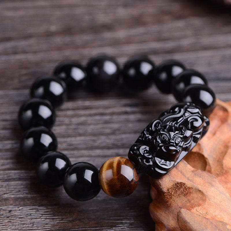 Obsidian Tiger Eye PiXiu Bracelet close-up on weathered wood, carved mythical beast detail, protective amulet