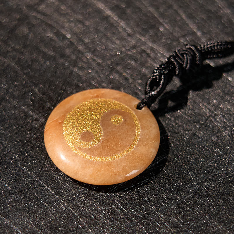 Yin Yang Crystal Necklace – Honey-toned stone round pendant with gold yin-yang etching, smooth polished amber stone on black 