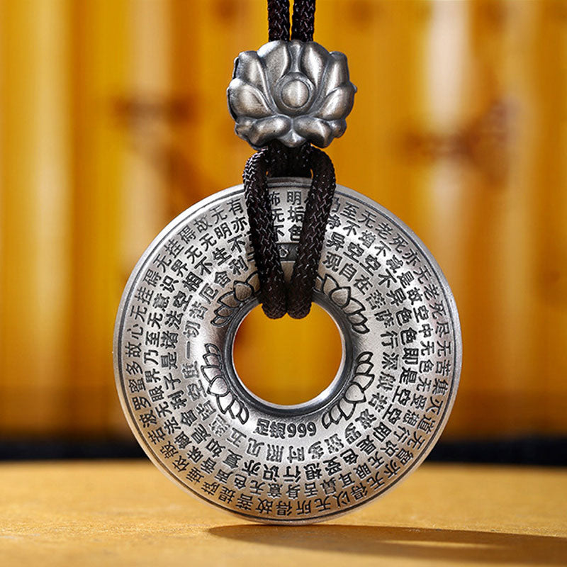 Silver Heart Sutra Pendant – 999 silver disc with sutra text and lotus cap on black cord, bamboo backdrop