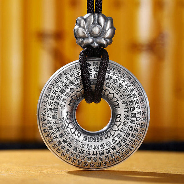 Silver Heart Sutra Pendant – 999 silver disc with sutra text and lotus cap on black cord, bamboo backdrop