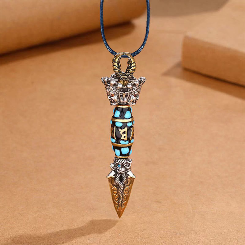 Tibetan Dzi Bead Dorje Pendant - Blue cord with gold bail on warm paper, showing turquoise barrel and serpent tip