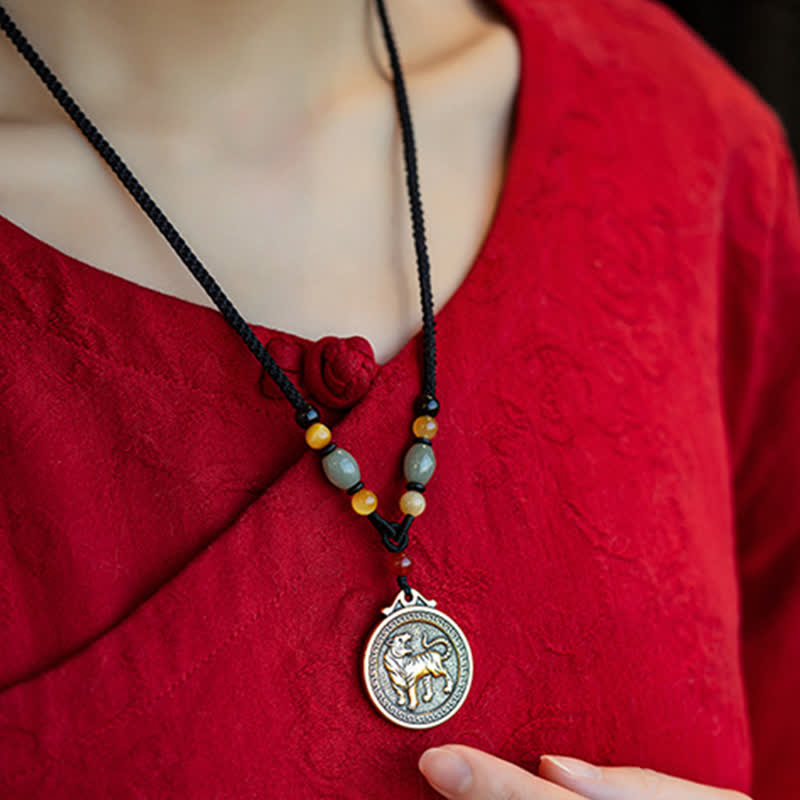 12 Chinese Zodiac Fortune Necklace Pendant – Dog zodiac pendant necklace on red traditional garment, silver medallion with gold dog relief and ornate border, black cord with jade amber and carnelian beads, Chinese zodiac birth year amulet jewelry