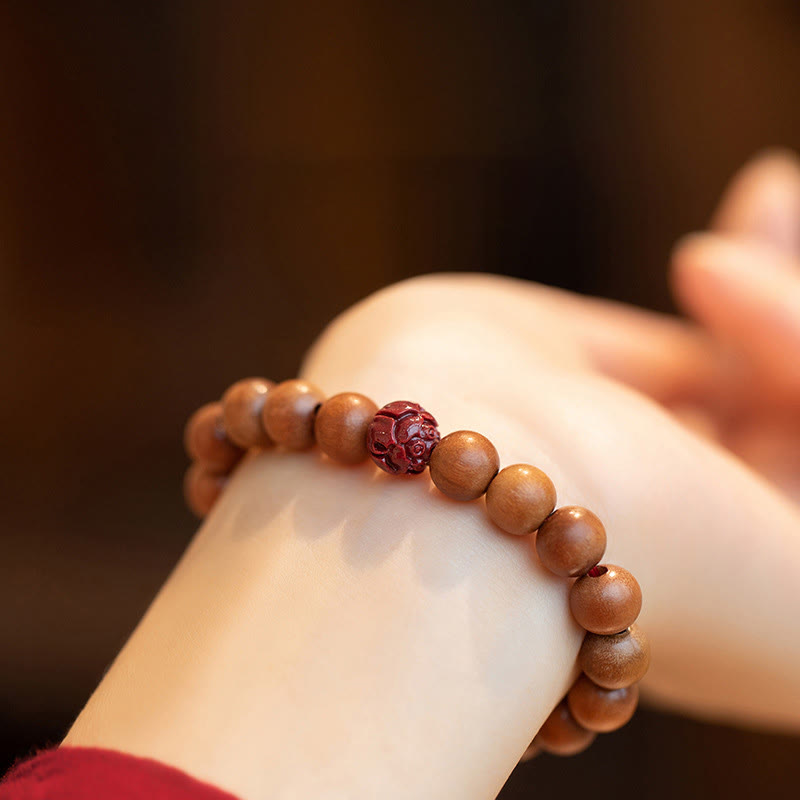 Peach Wood & Cinnabar Lotus Bracelet worn on wrist, warm brown wooden beads with carved red lotus accent, spiritual jewelry