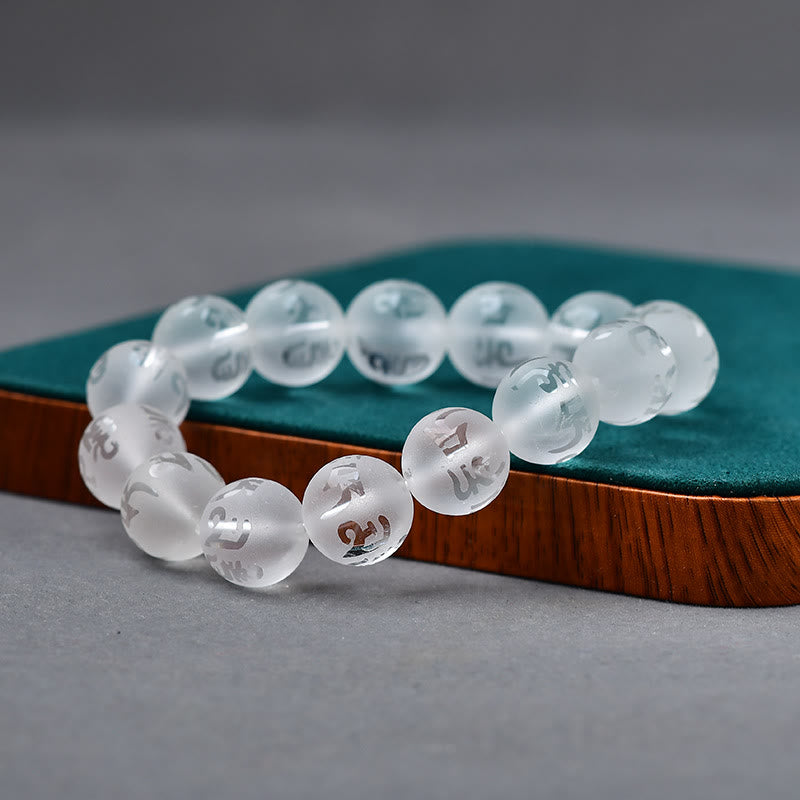 White Crystal Black Onyx Meditation Bracelet – Frosted clear quartz mantra beads on green velvet cushion with wood trim, gray gradient background, low side angle