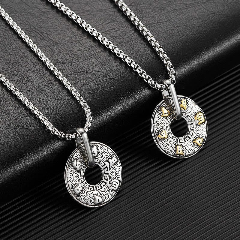 Tibetan Om Mani Padme Hum Peace Buckle Necklace – Two silver disc pendants with gold animal accents, one silver one gold-detail, on black leather surface diagonal