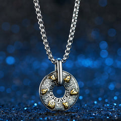 Tibetan Om Mani Padme Hum Peace Buckle Necklace – Silver pendant with spiral engravings and gold animal-head studs on box chain, deep blue glitter bokeh, frontal