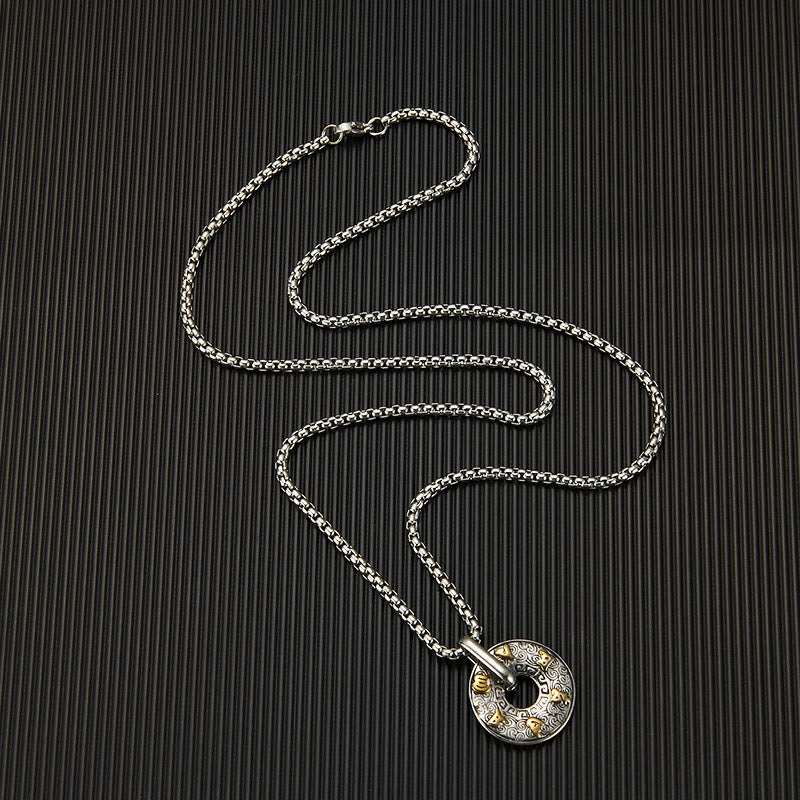 Tibetan Om Mani Padme Hum Peace Buckle Necklace – Silver pendant with gold accent engravings on dark vertically striped textured background, overhead angle