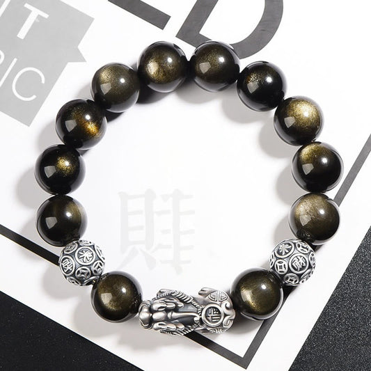 Gold Sheen Obsidian PiXiu Bracelet – Black gold-sheen beads with silver PiXiu on white magazine backdrop, wealth
