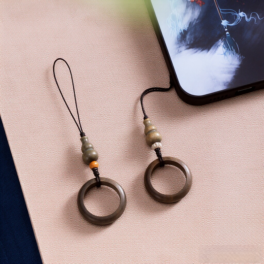 Sandalwood Phone Grip – Two green sandalwood ring grips with gourd beads on beige fabric beside phone, Feng Shui anti-drop charm