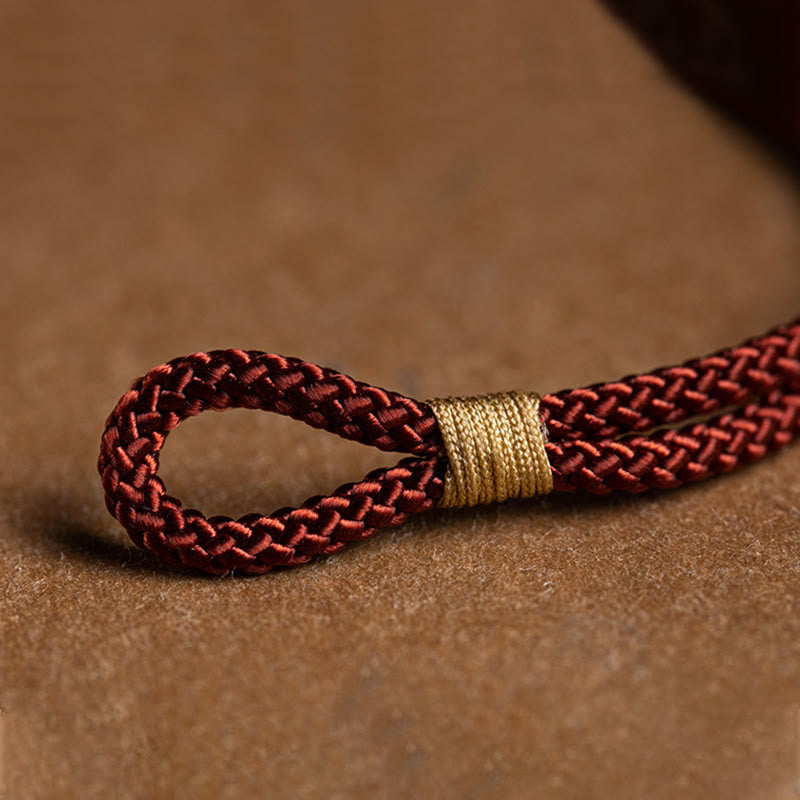 925 Silver Zodiac Natal Buddha Red String Bracelet macro detail of braided cord with gold coil wrap, loop closure mechanism, burgundy woven cord texture close-up, artisanal craftsmanship