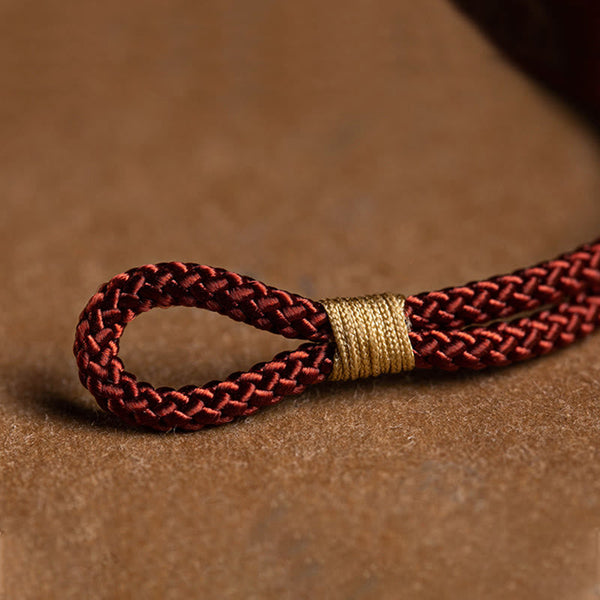 925 Silver Zodiac Natal Buddha Red String Bracelet macro detail of braided cord with gold coil wrap, loop closure mechanism, burgundy woven cord texture close-up, artisanal craftsmanship