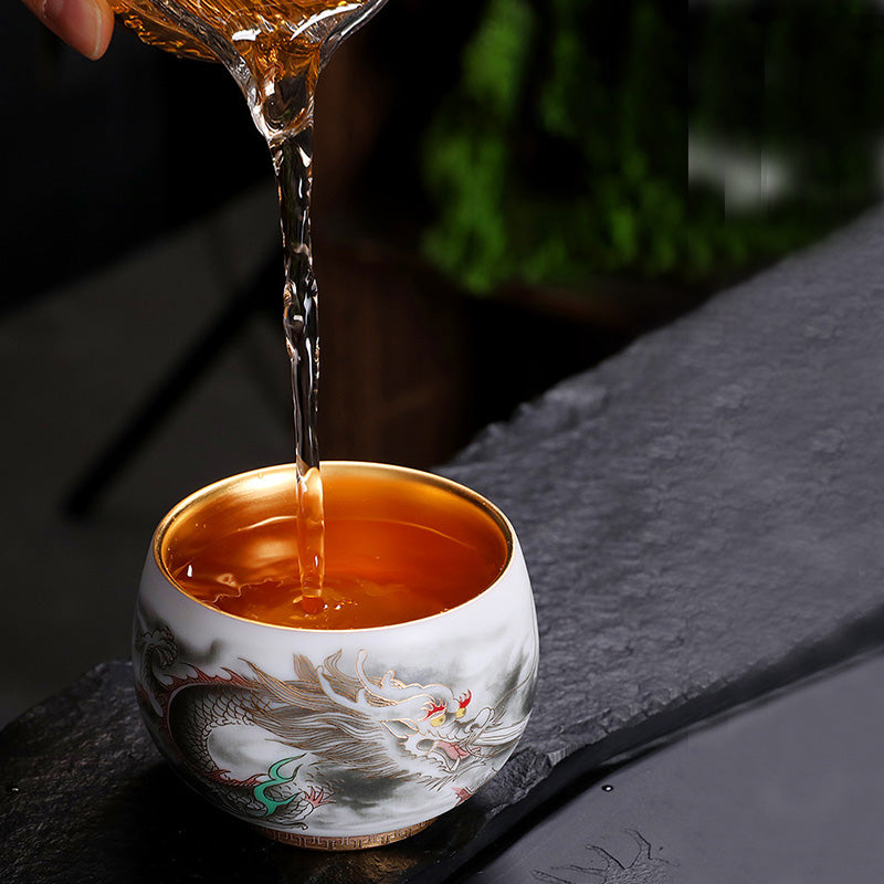 Dragon Gilt Porcelain Teacup - Amber tea poured into gold-rimmed dragon cup, tea ritual
