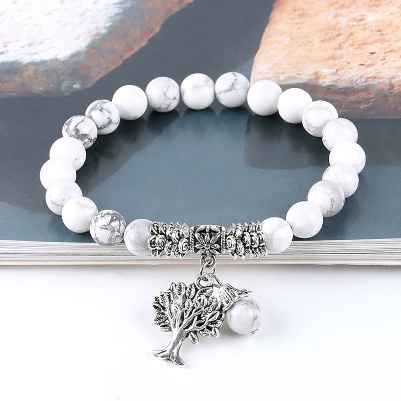 Tree of Life white turquoise bracelet with white howlite beads featuring gray veining, silver tree-of-life charm, silver floral spacers.