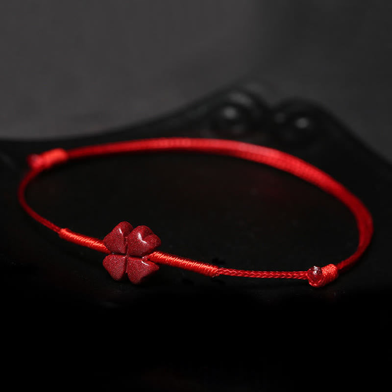 Cinnabar PiXiu Lotus Koi Fish Blessing Braid Bracelet – four-leaf clover design resting on black reflective surface, cinnabar handmade craft