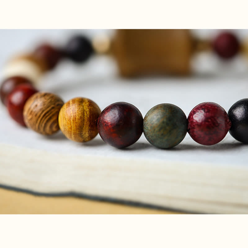 Multicolored Sandalwood Prayer Bracelet – Side angle on book page highlighting wood textures, mala beads