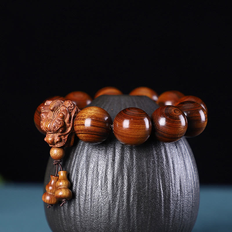 Multi-Wood Dragon Bracelet - Polished beads with carved dragon head and gourd charms on black ceramic, Strength