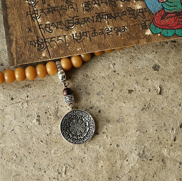 108 Bodhi Seed Mala Bracelet – Amber bodhi seed bracelet with silver medallion on manuscript
