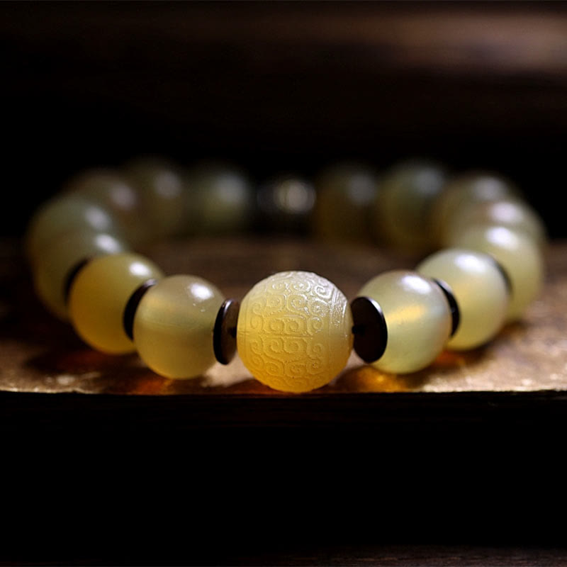 Tibetan Sheep Horn Skull Bracelet – Macro detail of carved cloud-pattern focal bead in amber material