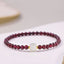 Natural garnet jade purification bracelet featuring deep wine-red garnet beads with a central white jade focal bead and gold spacer accents, displayed on white background
