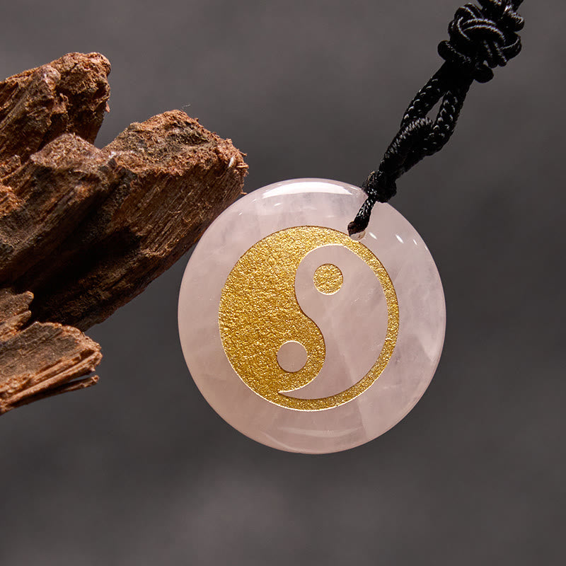 Yin Yang Crystal Necklace – Rose quartz round pendant with gold yin-yang inlay, pale pink translucent stone on black braided 
